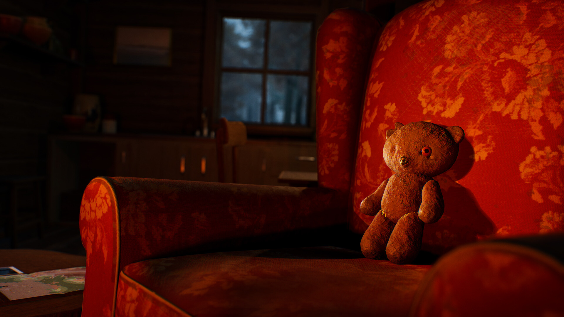 A worn teddy bear sitting on an ornate red chair in a cozy cabin setting.