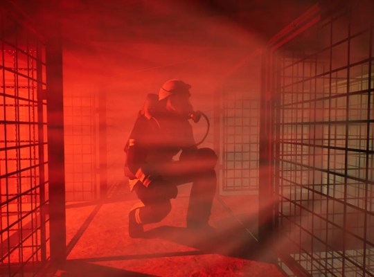 Firefighter in a smoky environment navigating through a dimly lit space